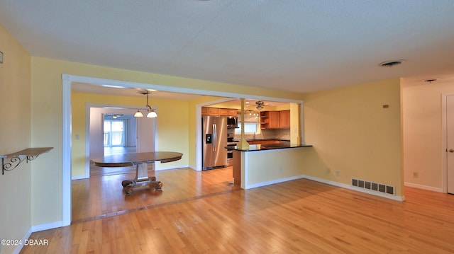 kitchen featuring sink, ceiling fan, light wood-type flooring, decorative light fixtures, and stainless steel appliances