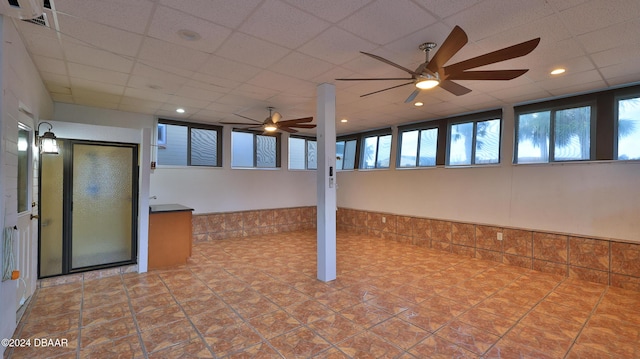 basement with a paneled ceiling and ceiling fan