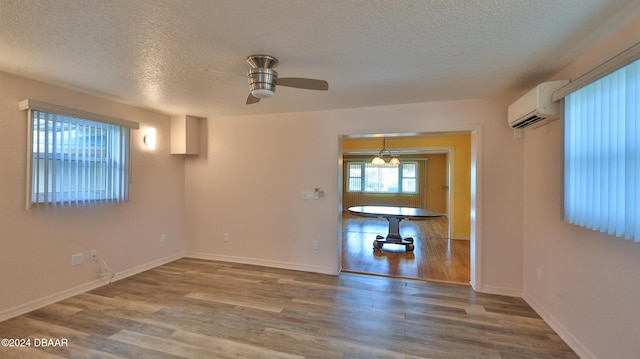 interior space featuring a wall mounted air conditioner, ceiling fan, hardwood / wood-style floors, and a textured ceiling