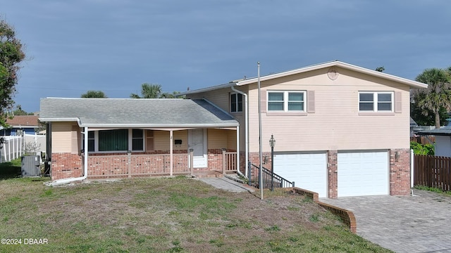 split level home with a garage, covered porch, and central air condition unit