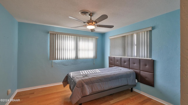 bedroom with ceiling fan, a textured ceiling, and light wood-type flooring