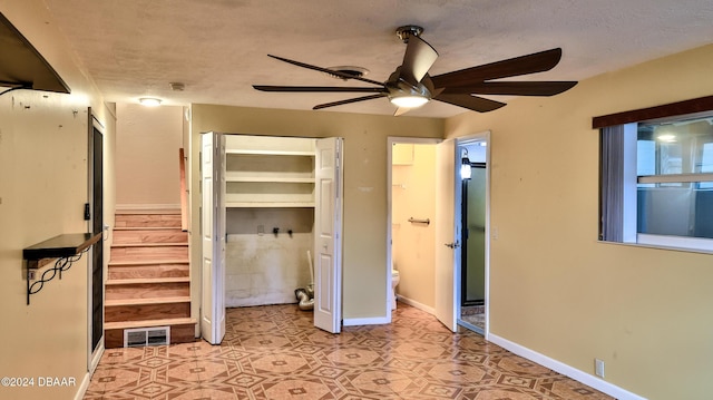 unfurnished bedroom with a textured ceiling, a closet, ceiling fan, and connected bathroom