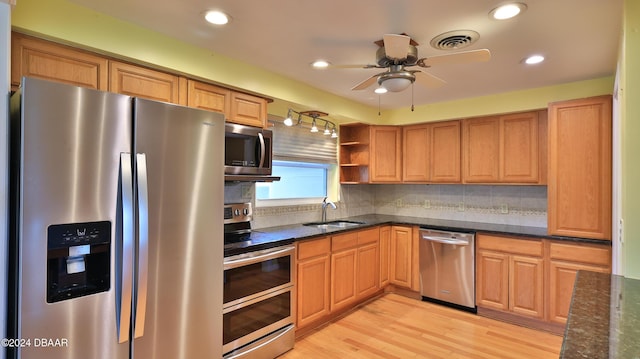 kitchen with ceiling fan, sink, backsplash, appliances with stainless steel finishes, and light wood-type flooring