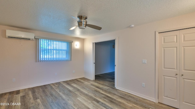 interior space featuring ceiling fan, a wall unit AC, a textured ceiling, a closet, and light wood-type flooring