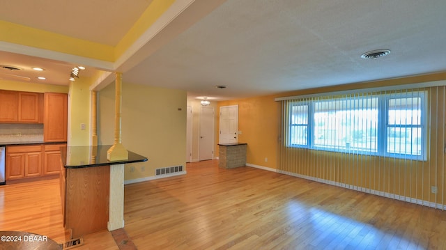 interior space with dishwasher, light wood-type flooring, a breakfast bar area, and tasteful backsplash