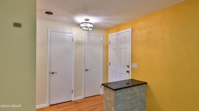 hall with a textured ceiling and light hardwood / wood-style flooring