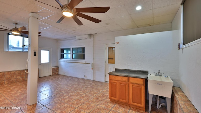 interior space with a drop ceiling, ceiling fan, and an AC wall unit