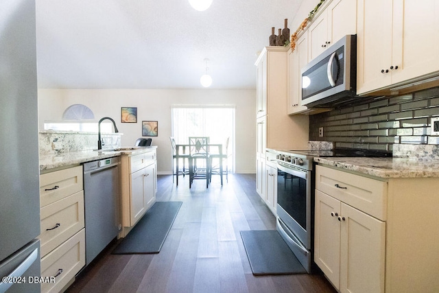 kitchen with stainless steel appliances, dark wood-type flooring, light stone counters, white cabinets, and backsplash