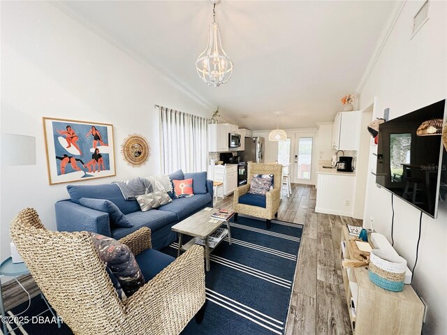 84 Heather Point Ct, New Smyrna Beach, FL 32169 - living room with light wood-style flooring, a chandelier, vaulted ceiling, and ornamental molding