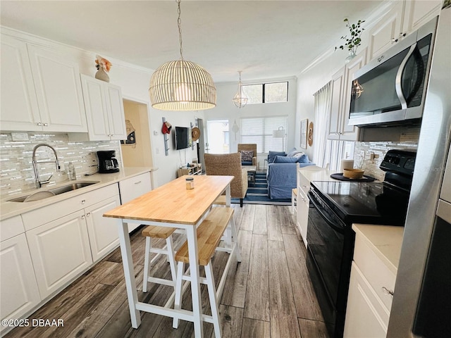 84 Heather Point Ct, New Smyrna Beach, FL 32169 - kitchen with black range with electric cooktop, stainless steel microwave, a sink, tasteful backsplash, and light wood-type flooring