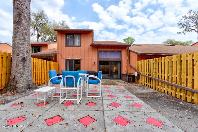rear view of house featuring board and batten siding, a patio, and a fenced backyard