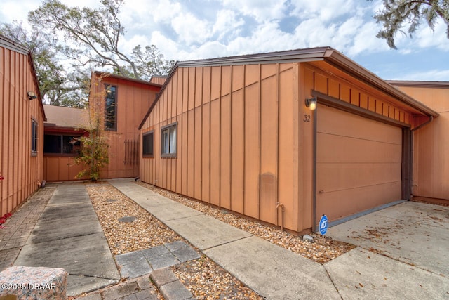 view of side of home featuring board and batten siding, an attached garage, and concrete driveway