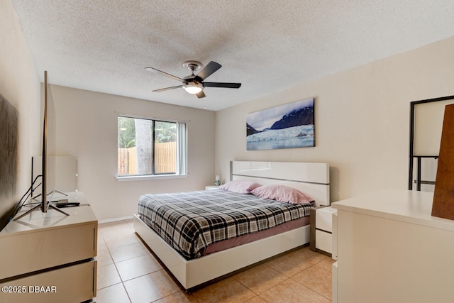 bedroom featuring light tile patterned floors, a textured ceiling, ceiling fan, and baseboards