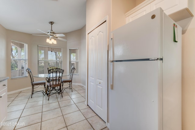 dining space with light tile patterned floors, a ceiling fan, plenty of natural light, and baseboards