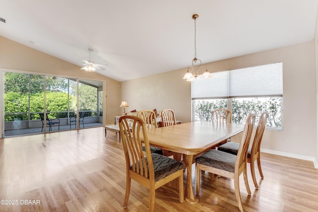 dining space featuring ceiling fan with notable chandelier, lofted ceiling, light wood-style floors, and baseboards