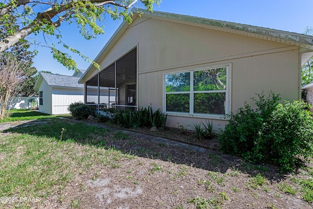 view of side of property featuring a lawn and a sunroom