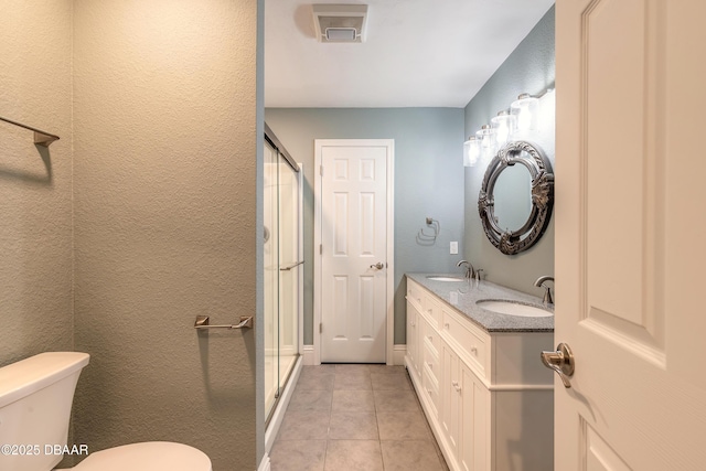 bathroom with tile patterned floors, toilet, vanity, and a shower with door