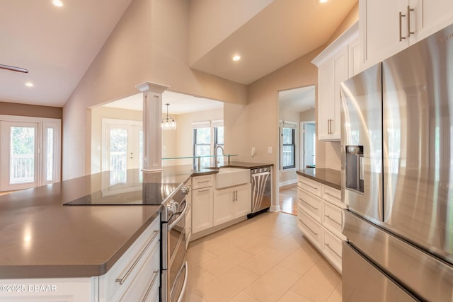 kitchen featuring lofted ceiling, sink, ornate columns, appliances with stainless steel finishes, and white cabinets