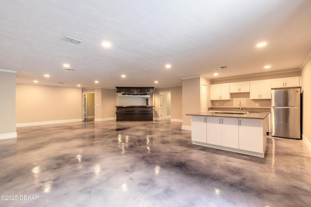 kitchen with white cabinets, concrete floors, stainless steel fridge, sink, and a large island with sink