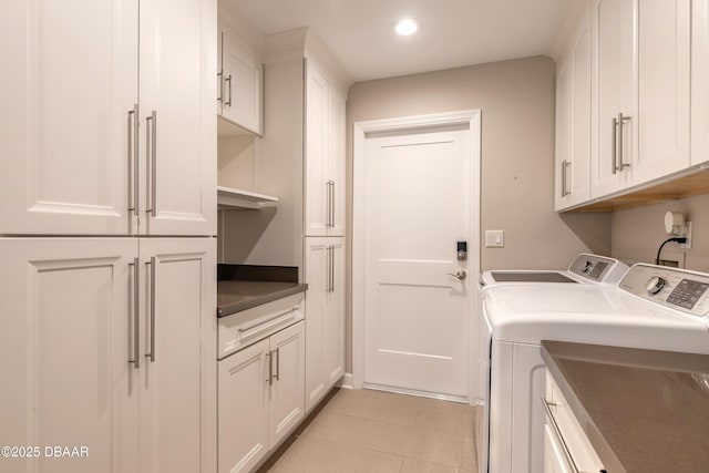 laundry room with washing machine and dryer, light tile patterned floors, and cabinets