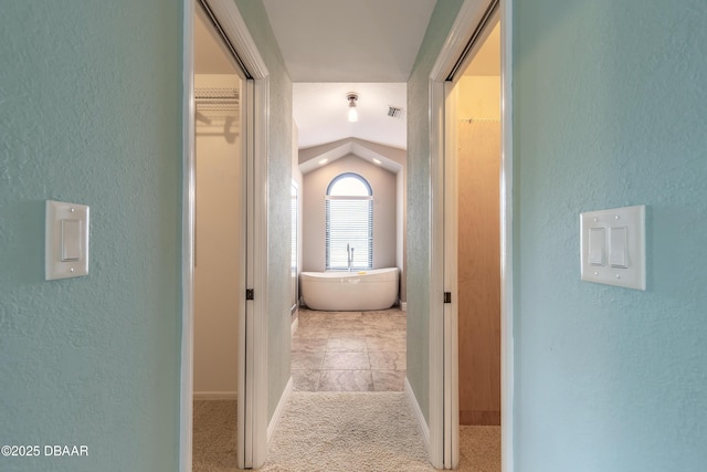 hall featuring lofted ceiling and light colored carpet