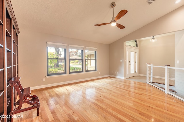 unfurnished living room featuring ceiling fan, vaulted ceiling, a textured ceiling, and light hardwood / wood-style flooring