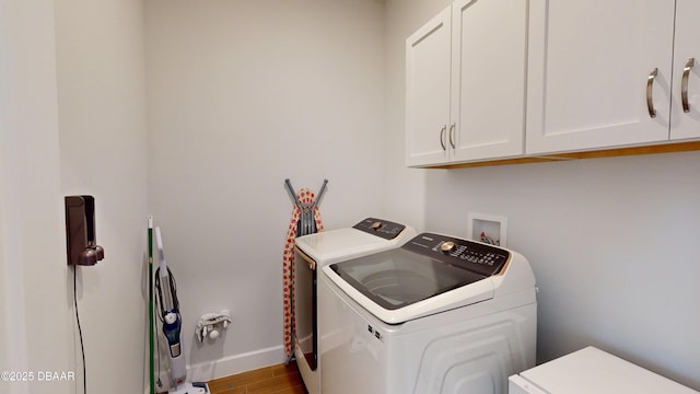 washroom with baseboards, cabinet space, wood finished floors, and washer and clothes dryer