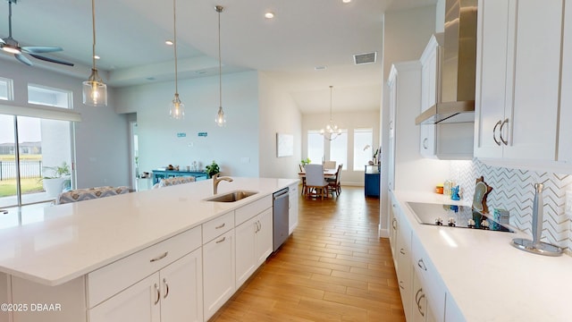 kitchen with visible vents, a sink, black electric stovetop, wall chimney range hood, and stainless steel dishwasher