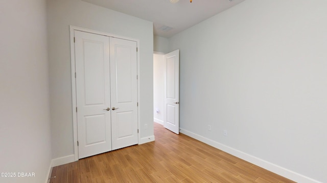 unfurnished bedroom with baseboards, a closet, and light wood-style flooring