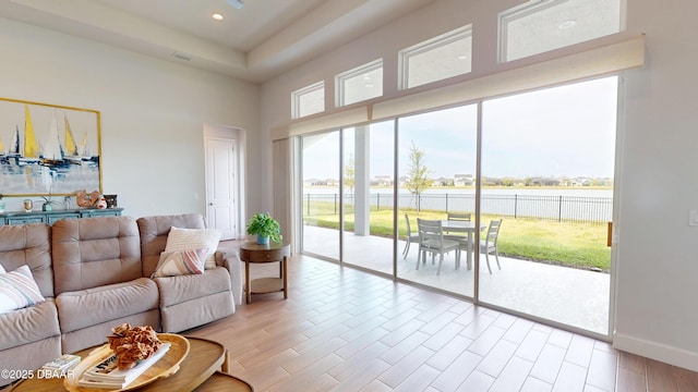 living area featuring a high ceiling, baseboards, light wood-style flooring, and recessed lighting
