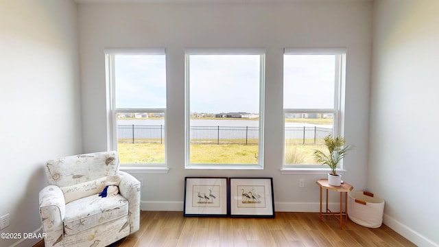 sitting room with baseboards, light wood-type flooring, and a water view