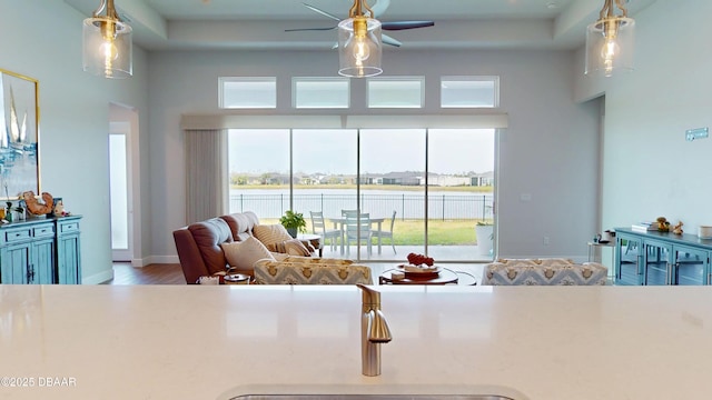 interior space featuring a water view, baseboards, hanging light fixtures, ceiling fan, and wood finished floors