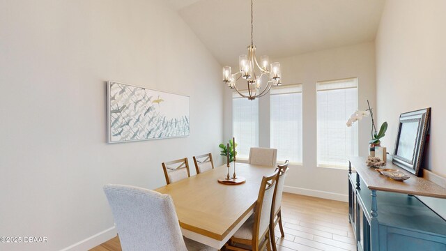 dining area with baseboards, lofted ceiling, a notable chandelier, and light wood finished floors