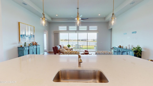 kitchen featuring hanging light fixtures, ceiling fan, a sink, and open floor plan