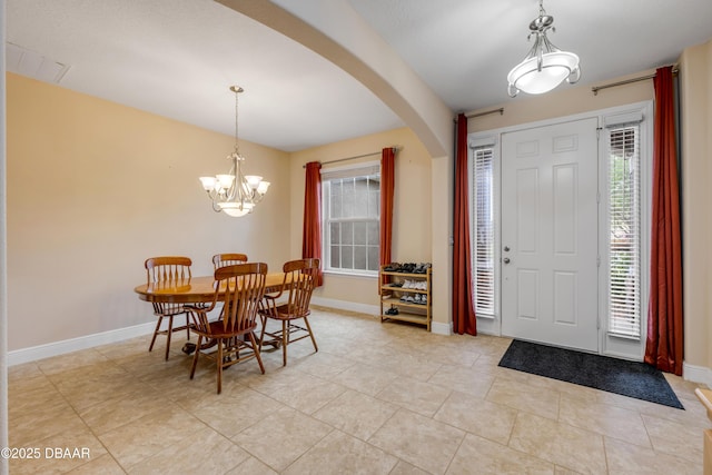 foyer featuring baseboards, light tile patterned floors, arched walkways, and a notable chandelier