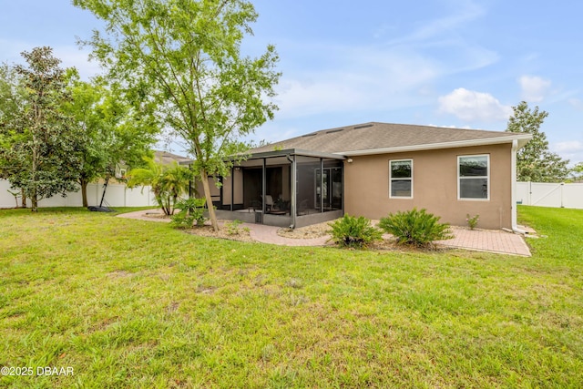 back of house featuring stucco siding, a fenced backyard, a yard, and a sunroom