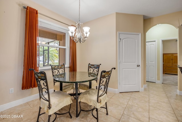 dining room with a chandelier, baseboards, arched walkways, and light tile patterned floors