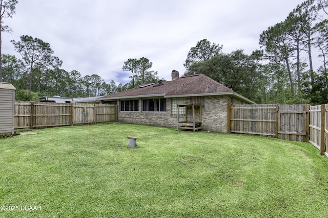 255 Woodhaven Cir W, Ormond Beach, FL 32174 - rear view of house featuring brick siding, a chimney, a fenced backyard, and a shingled roof