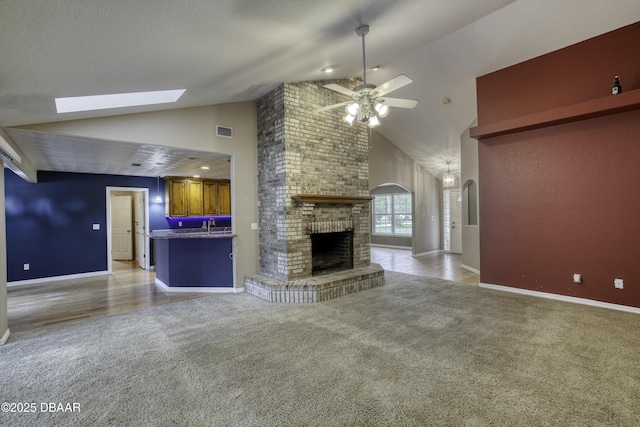 255 Woodhaven Cir W, Ormond Beach, FL 32174 - unfurnished living room with carpet floors, ceiling fan, high vaulted ceiling, a brick fireplace, and a skylight