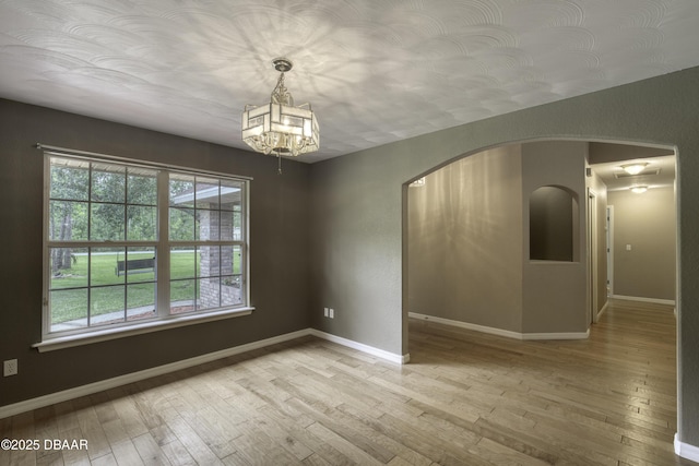 255 Woodhaven Cir W, Ormond Beach, FL 32174 - spare room featuring hardwood / wood-style flooring, arched walkways, and a chandelier