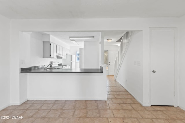 kitchen with kitchen peninsula, white cabinetry, sink, and white appliances