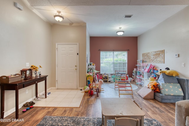 rec room featuring a textured ceiling and light wood-type flooring