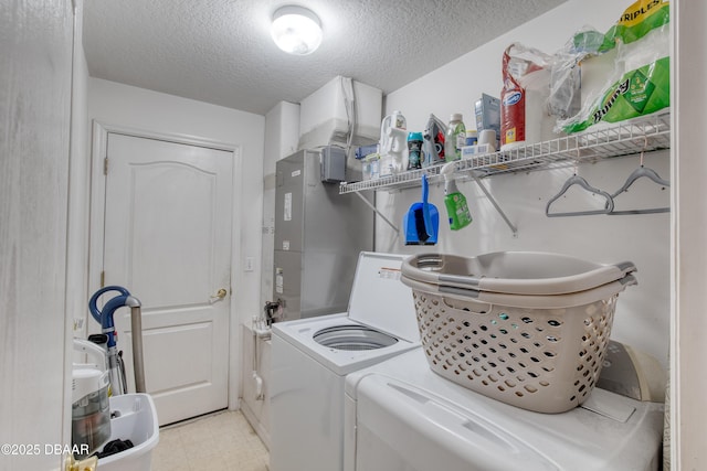 clothes washing area with a textured ceiling and washer and clothes dryer