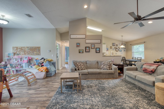 living room with hardwood / wood-style flooring, ceiling fan, vaulted ceiling, and a textured ceiling