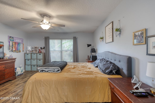 bedroom featuring ceiling fan, hardwood / wood-style floors, and a textured ceiling