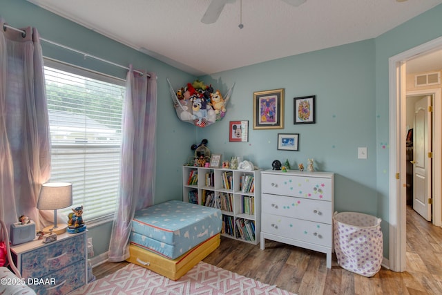 bedroom featuring hardwood / wood-style flooring, a textured ceiling, and ceiling fan