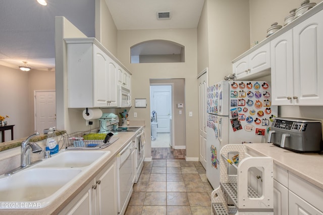 kitchen with white cabinetry, white appliances, and sink