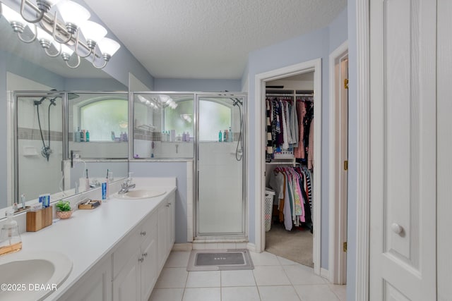 bathroom featuring tile patterned flooring, vanity, a textured ceiling, and walk in shower