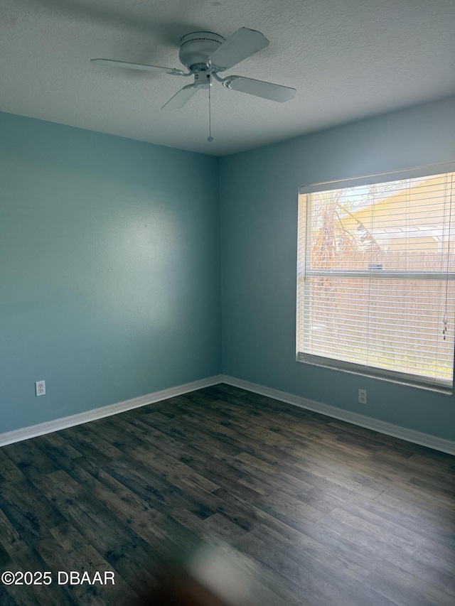 spare room featuring a textured ceiling, dark wood-style flooring, and baseboards