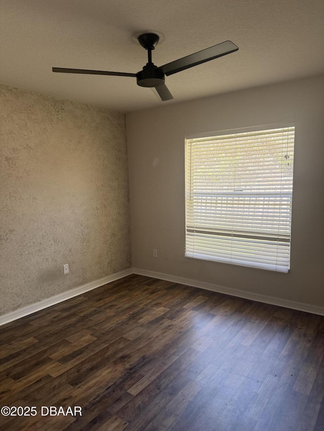 empty room featuring baseboards, dark wood finished floors, and a ceiling fan